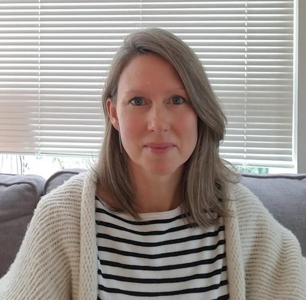 Rebecca smiling, wearing a striped shirt and a sweater