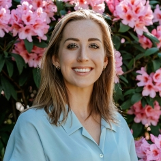 Nicole smiling, flowers behind her