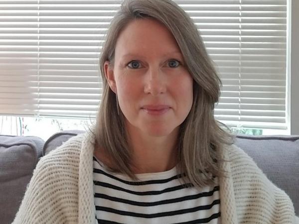 Rebecca smiling, wearing a striped shirt and sweater